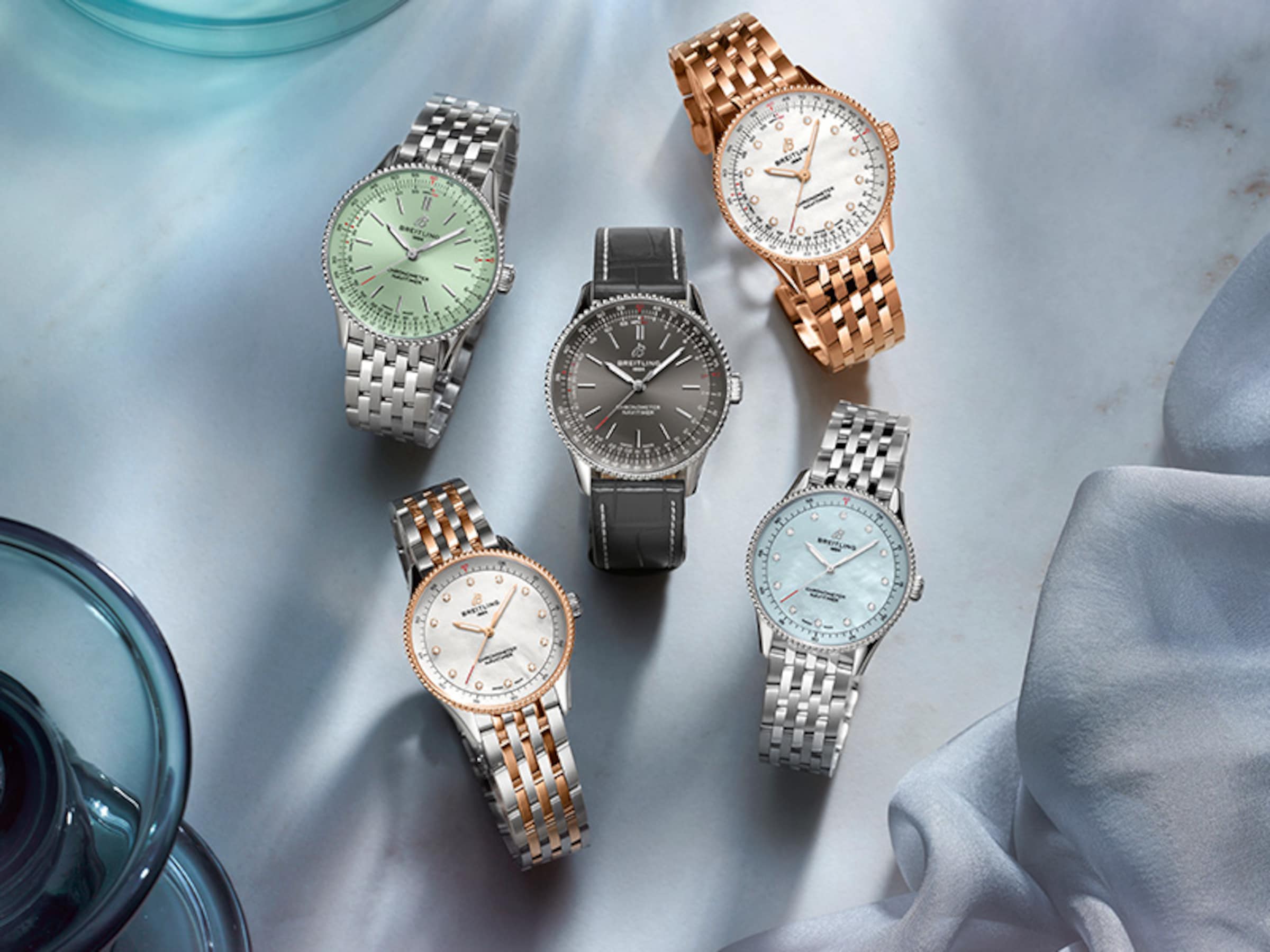 五枚不同顏色錶盤的 Navitimer 腕錶擺放在一塊藍布上。