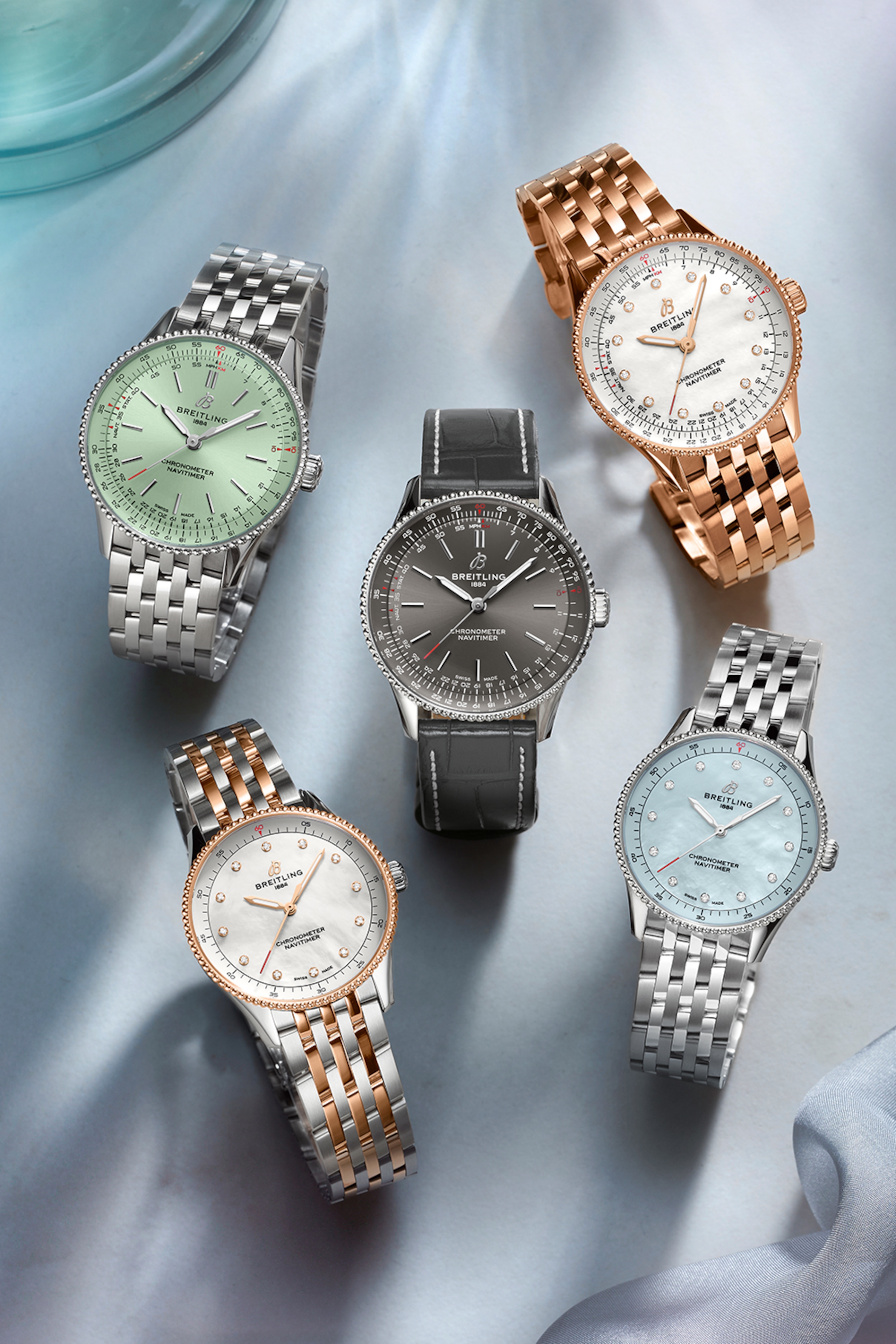 五枚不同顏色錶盤的 Navitimer 腕錶擺放在一塊藍布上。